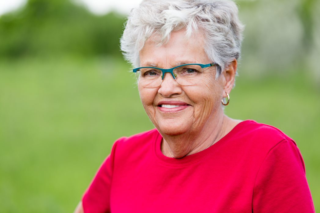 older woman in red shirt smiling at camera
