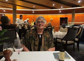 Patsy sitting at table with drinks, smiling