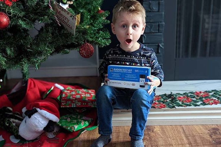 young boy holding a radon kit with an excited face