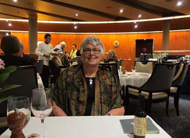 Patsy sitting at table with drinks, smiling