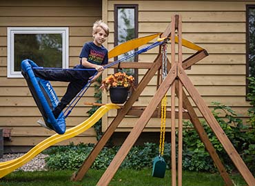 Reid playing on his playground swing smiling